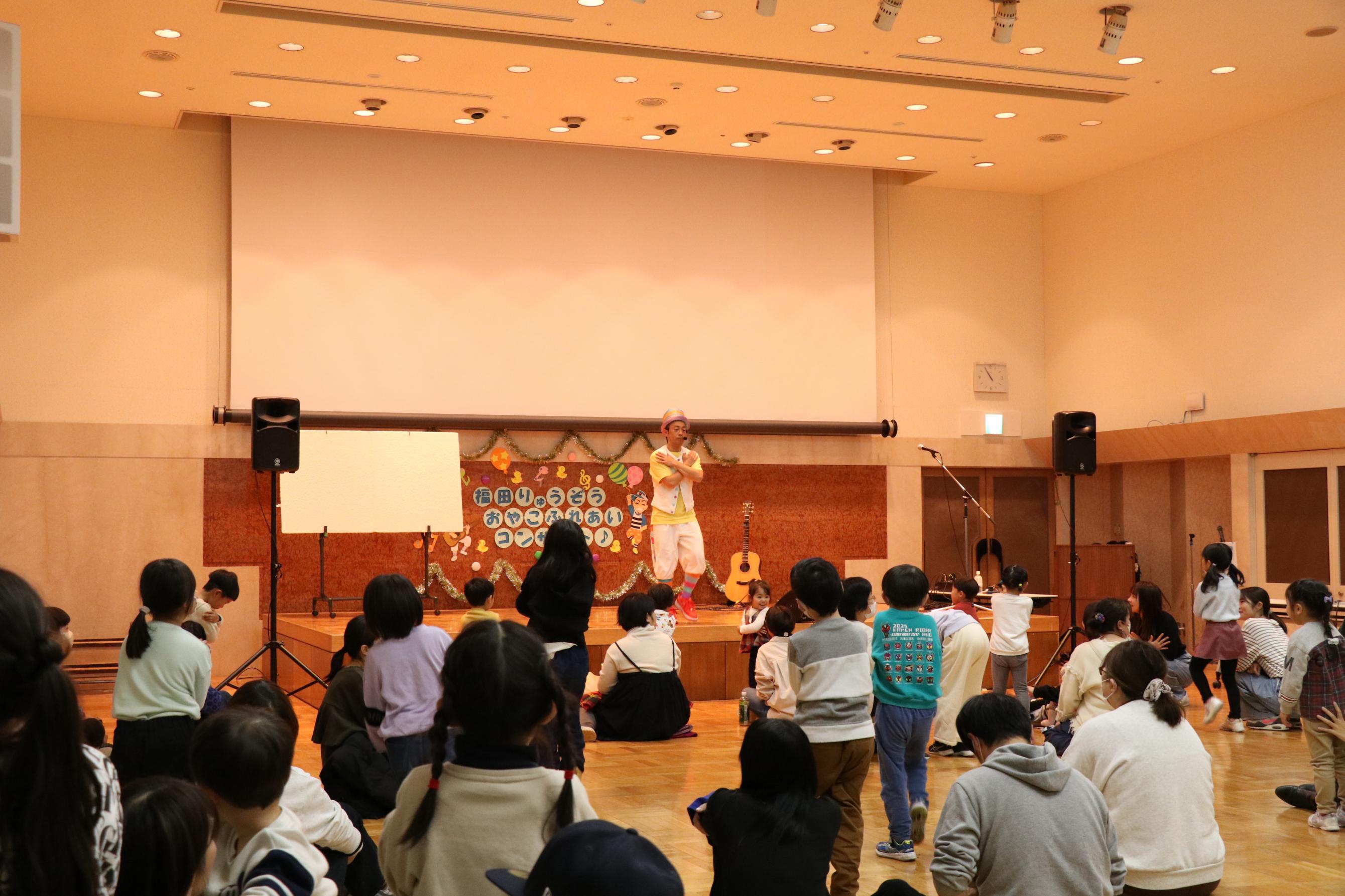 福田りゅうぞうコンサートのステージの様子と児童の様子