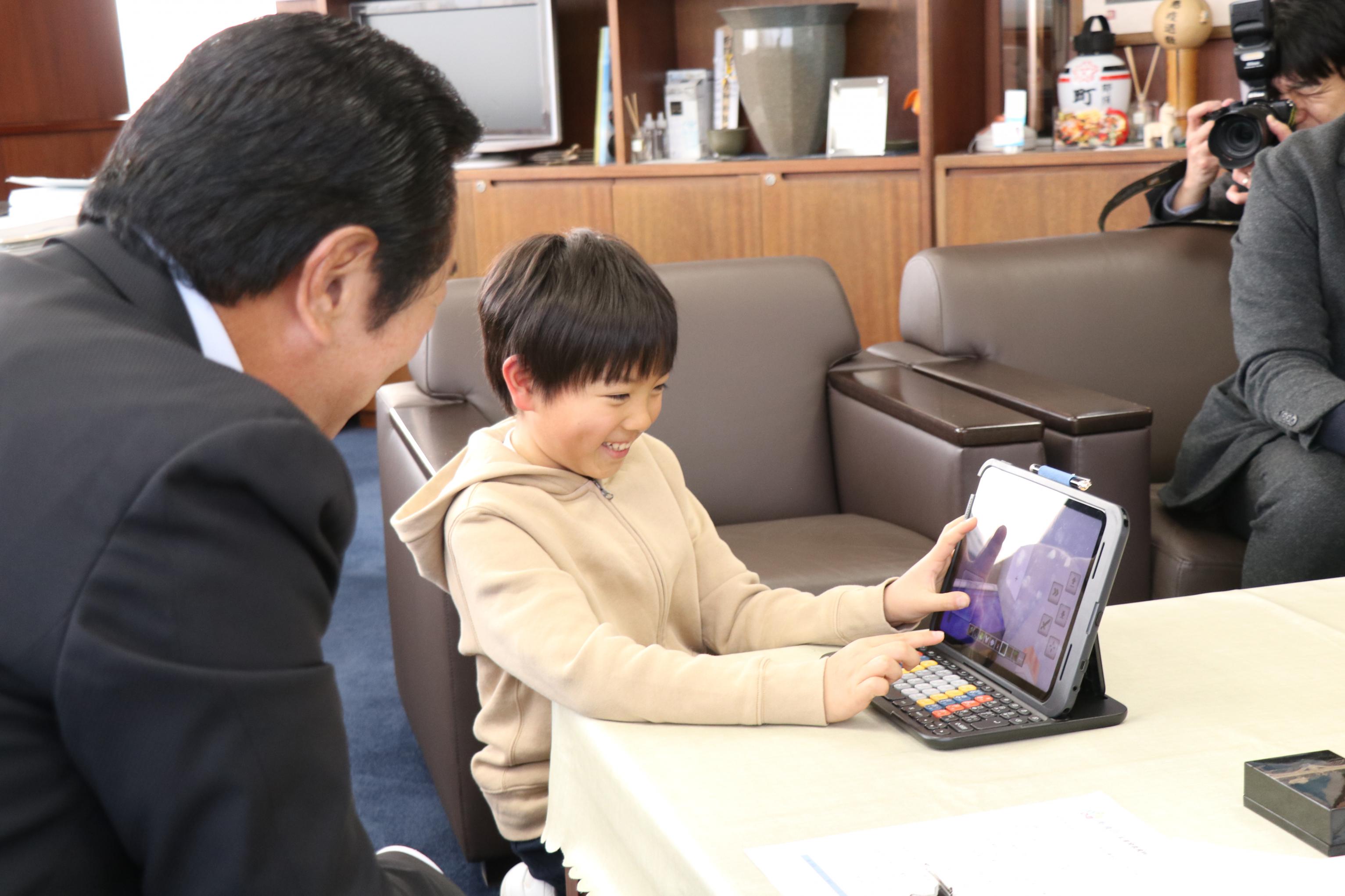 砂川さんが平山町長に作成した作品を説明する様子 砂川さんが平山町長に作成した作品を説明する様子