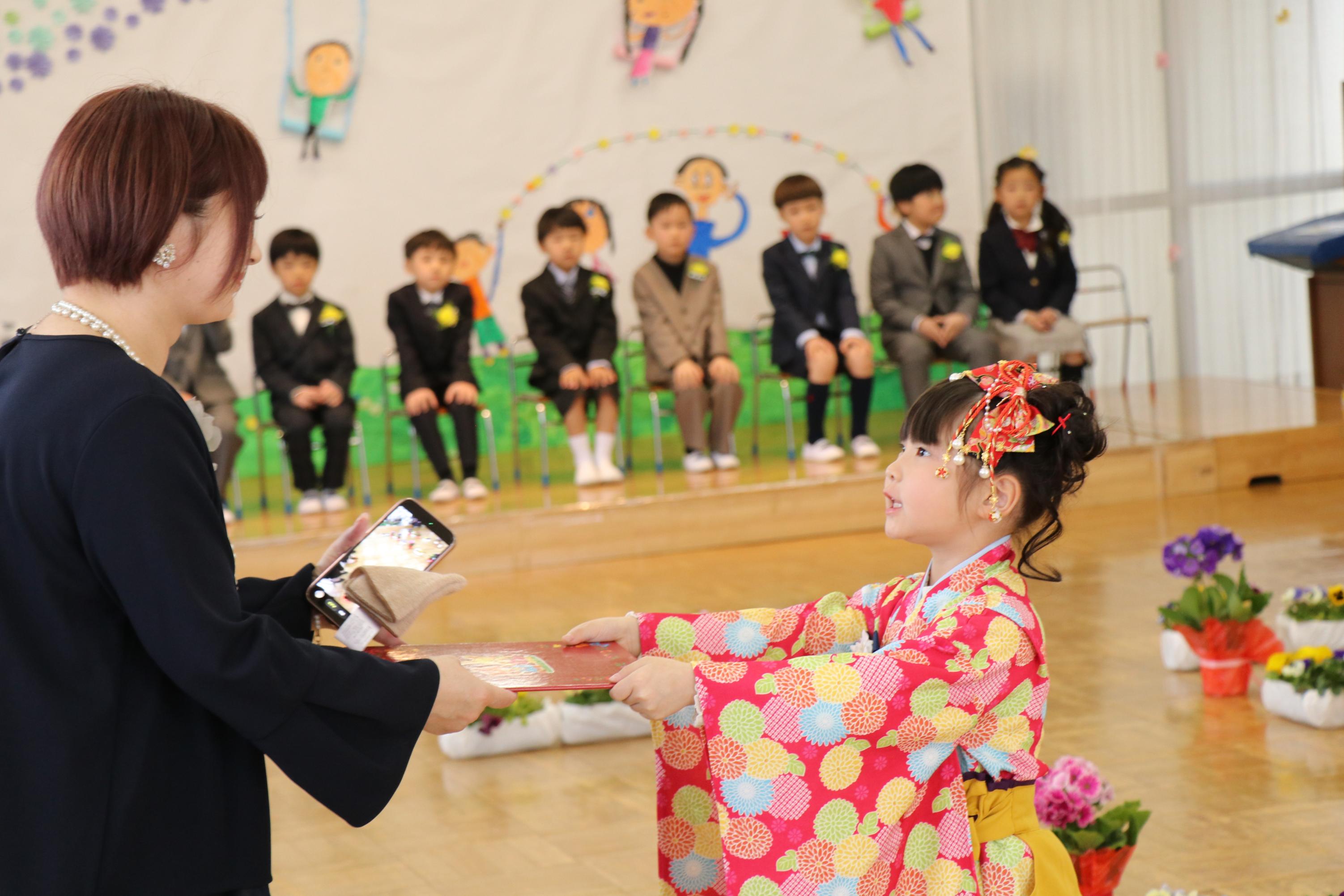 園児が受け取った修了証書を母親に手渡す様子 園児が受け取った修了証書を母親に手渡す様子